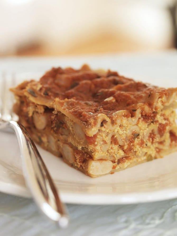 A slice of vegan lasagna on a white plate with a silver fork.