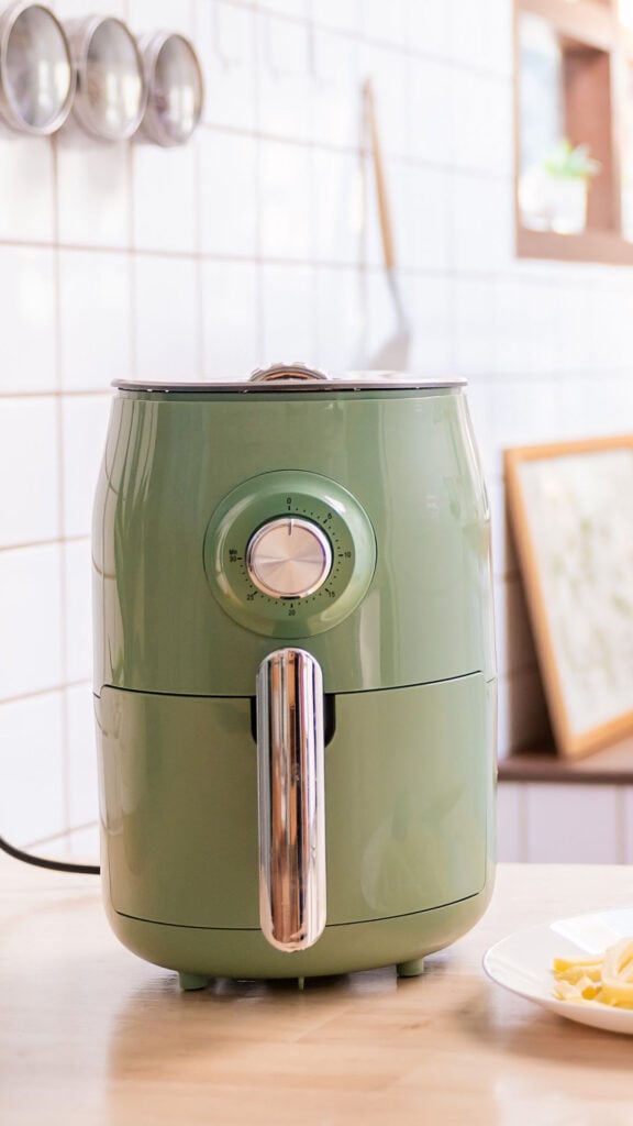 green air fryer on a white kitchen counter.