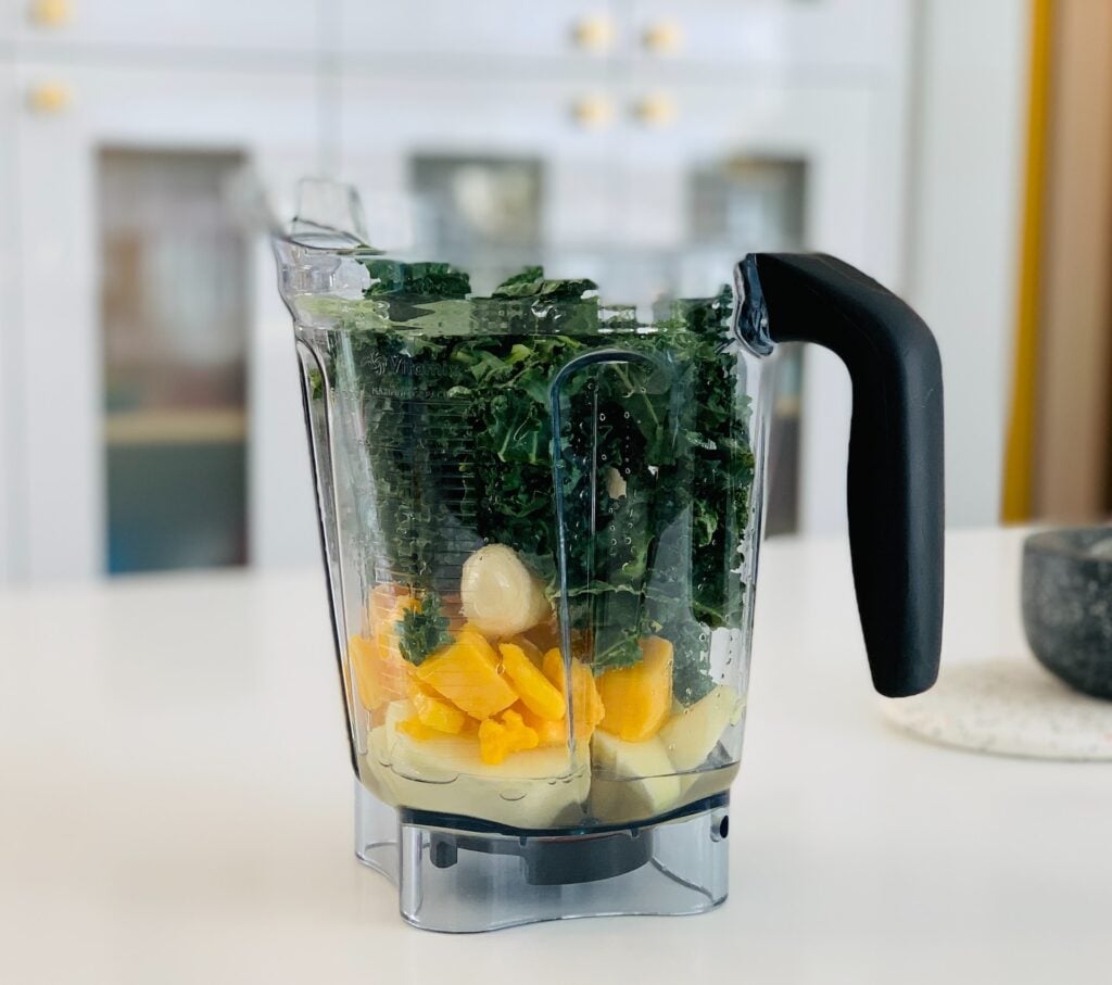 Vitamix blender with smoothie ingredients layered in.