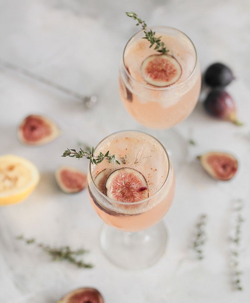 Fig shrub mocktail in a wine glass with a sprig of thyme
