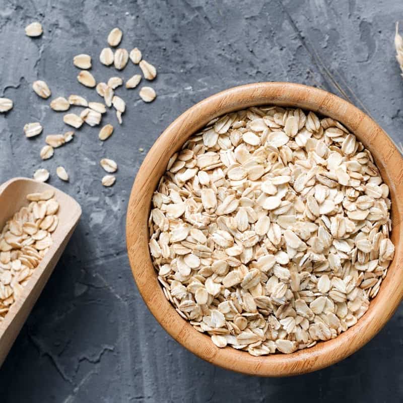 Rolled oats on a wooden bowl placed on a stone surface