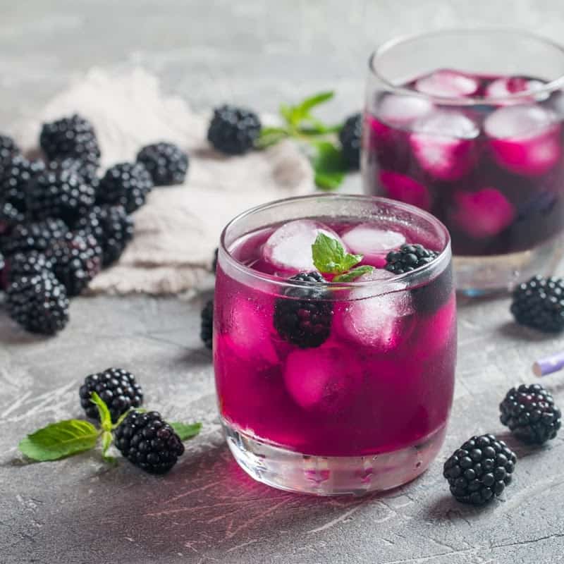 Blackberry syrup used in a purple mocktail garnished with fresh blackberries