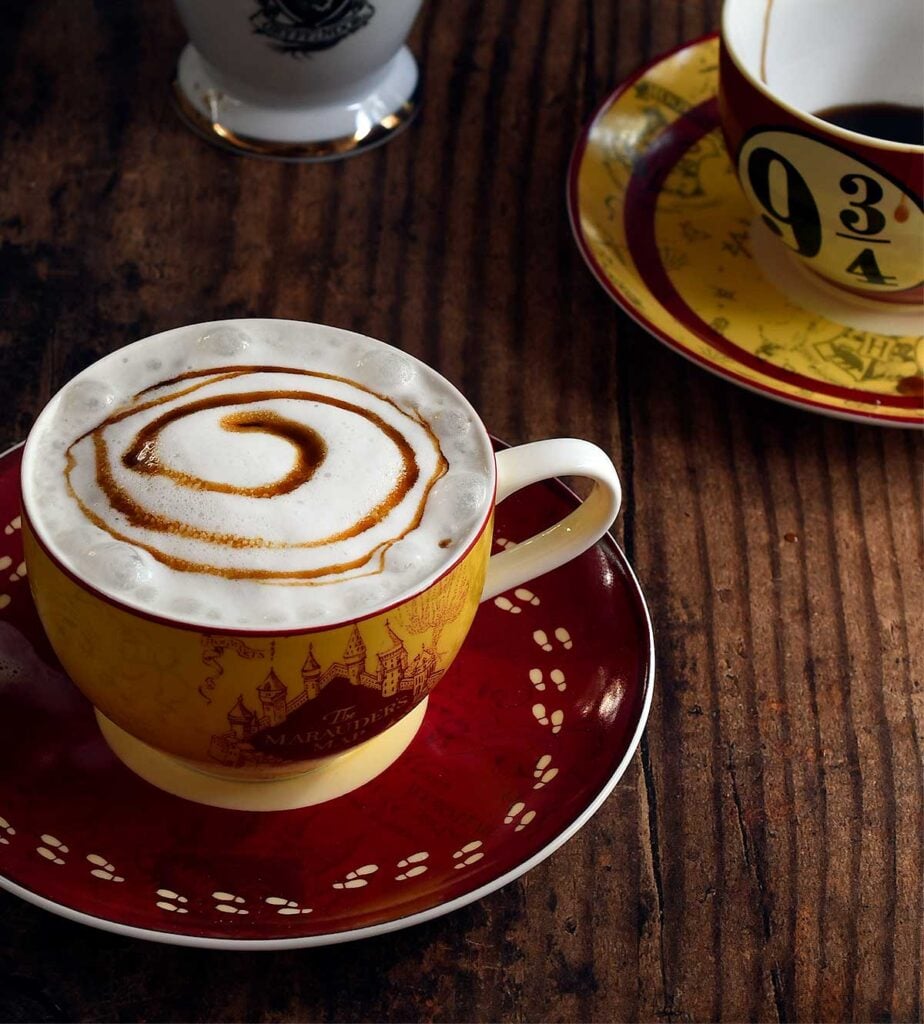 Butterbeer with foamed milk topping on a mischief managed tea cup topped with with a butterbeer syrup swirl