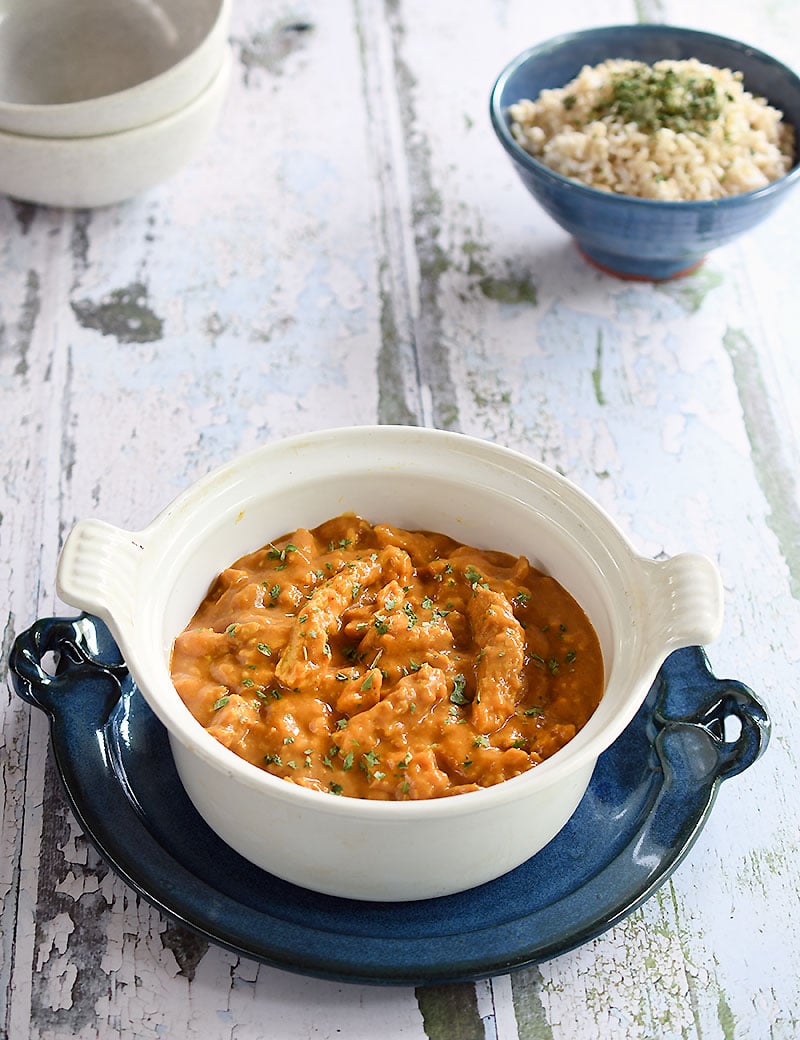 vegan butter chicken made with soy curls in a white Le Cresuet pot on a peeling paint tablevegan butter chicken made with soy curls in a white Le Cresuet pot on a peeling paint table