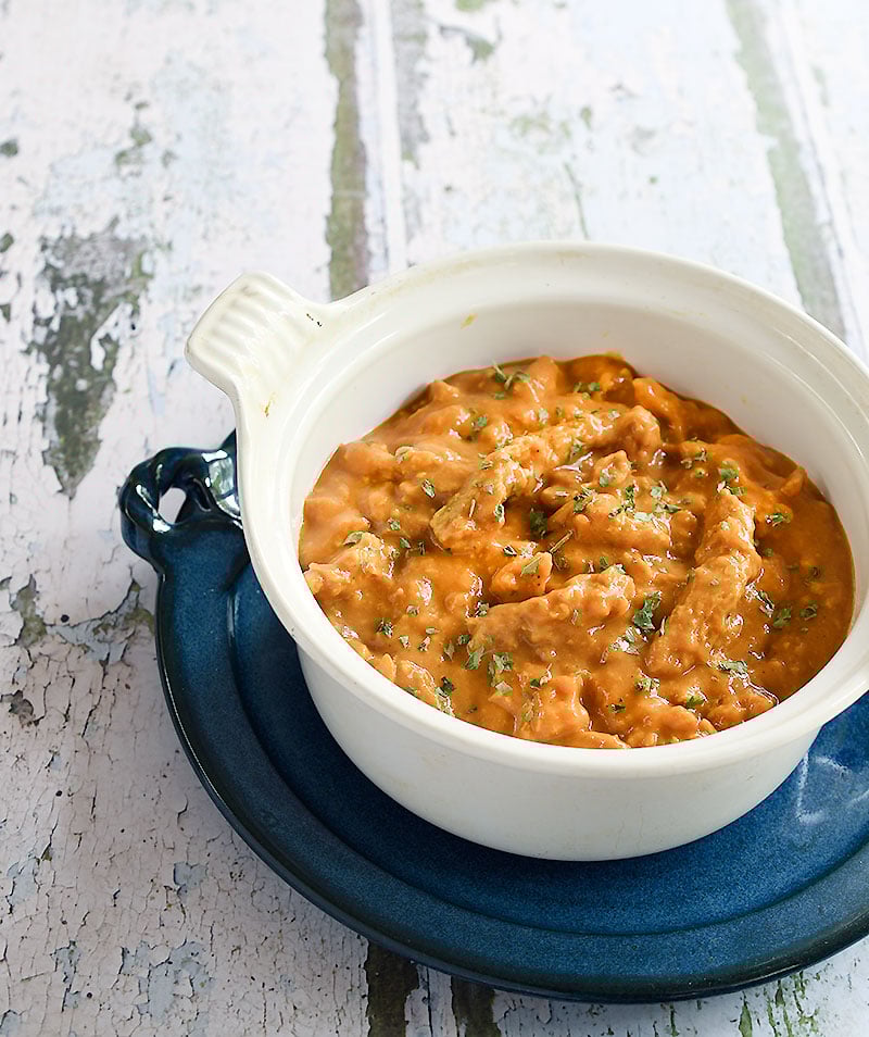 vegan butter chicken made with soy curls in a white Le Cresuet pot on a blue ceramic plate