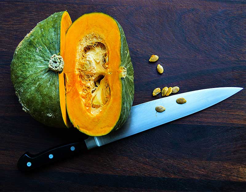 Buttercup squash cut in half on a dark wooden cutting board.