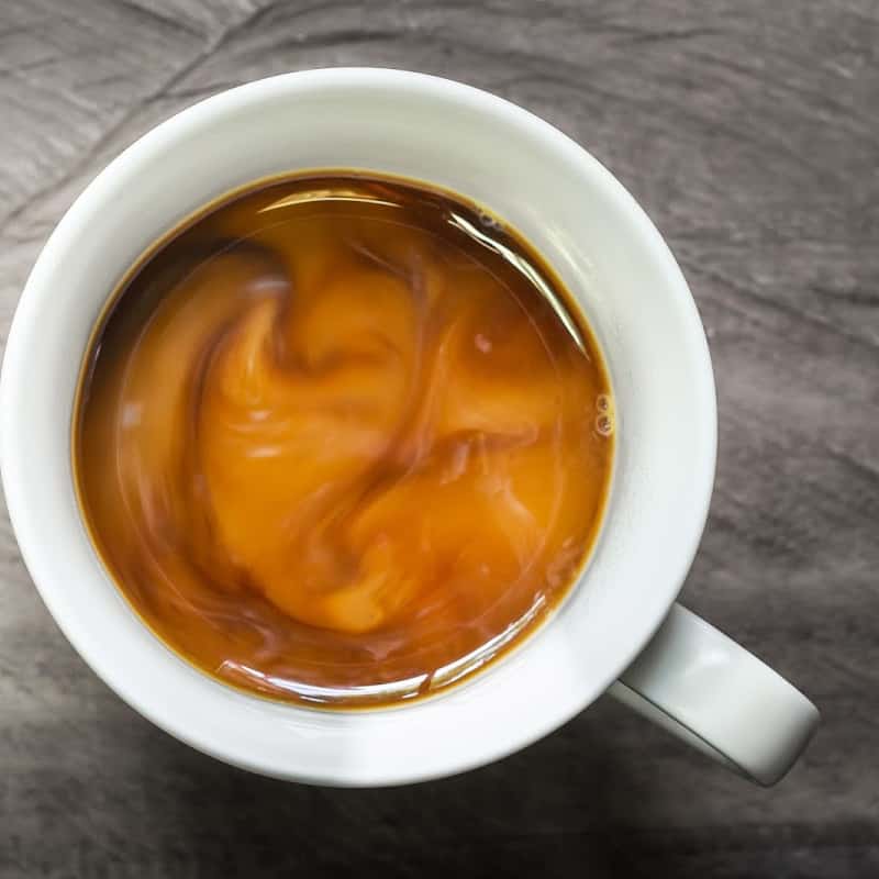 White cup filled with coffee and vegan creamer 