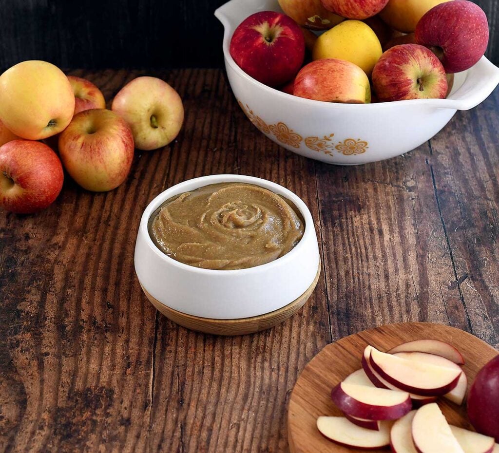 Date caramel vegan hummus swirled in a white bowl on a dark wooden table.