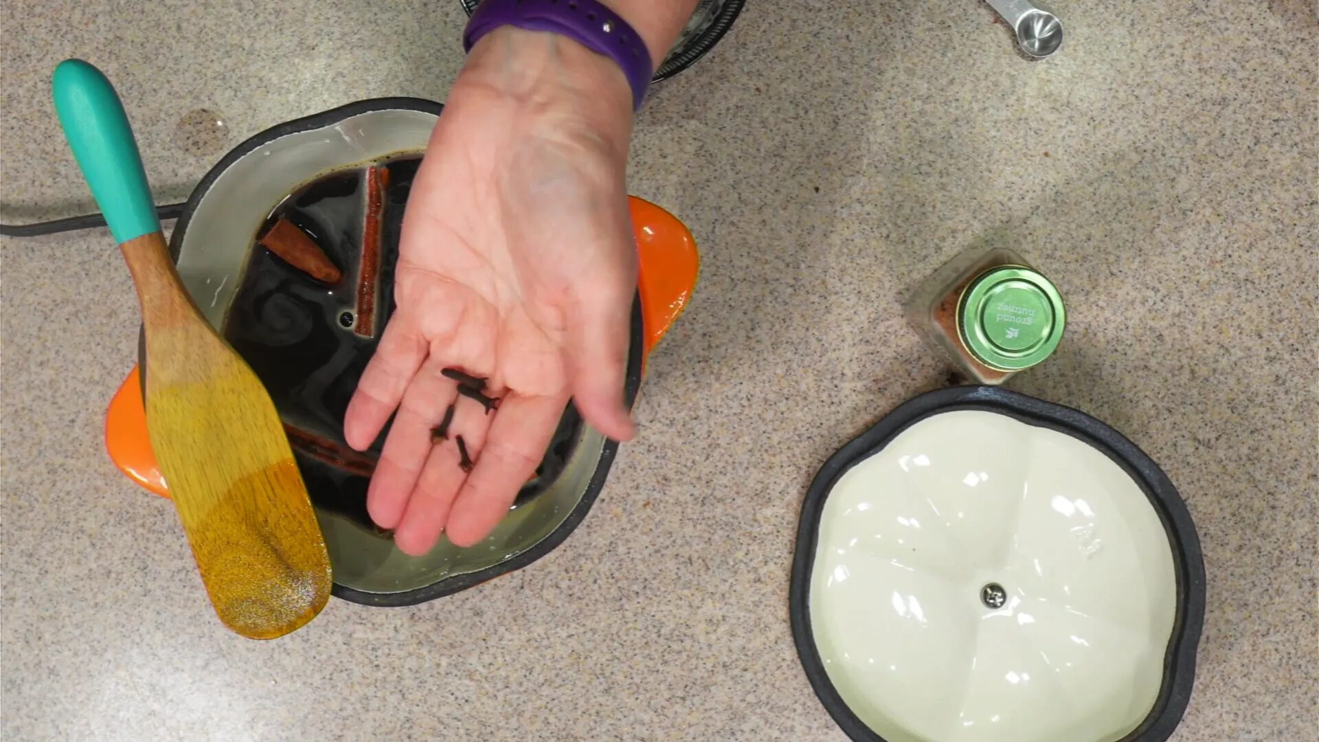 Adding whole cloves to the mixture.