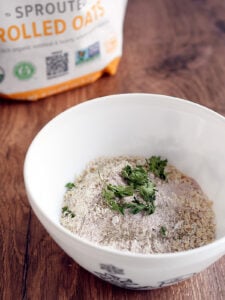 Dry ingredients for oat matzo balls in white bowl on a wooden table.