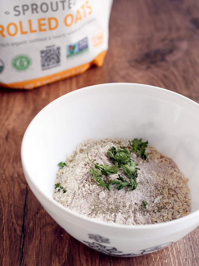 Dry ingredients for oat matzo balls in white bowl on a wooden table.