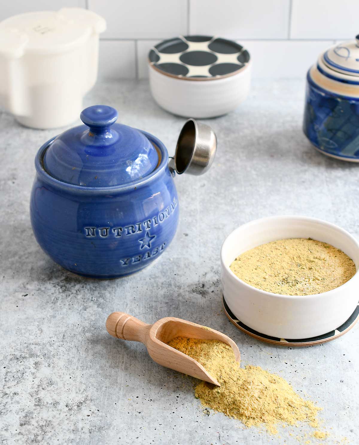 Vegan bouillon powder in a white bowl with a blue nutritional yeast jar.