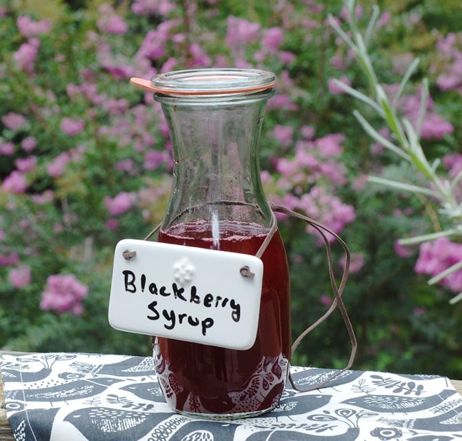 DIY Fresh Blackberry Syrup DIY Fresh Blackberry Syrup in a weck carafe with pink crepe myrtles in the background