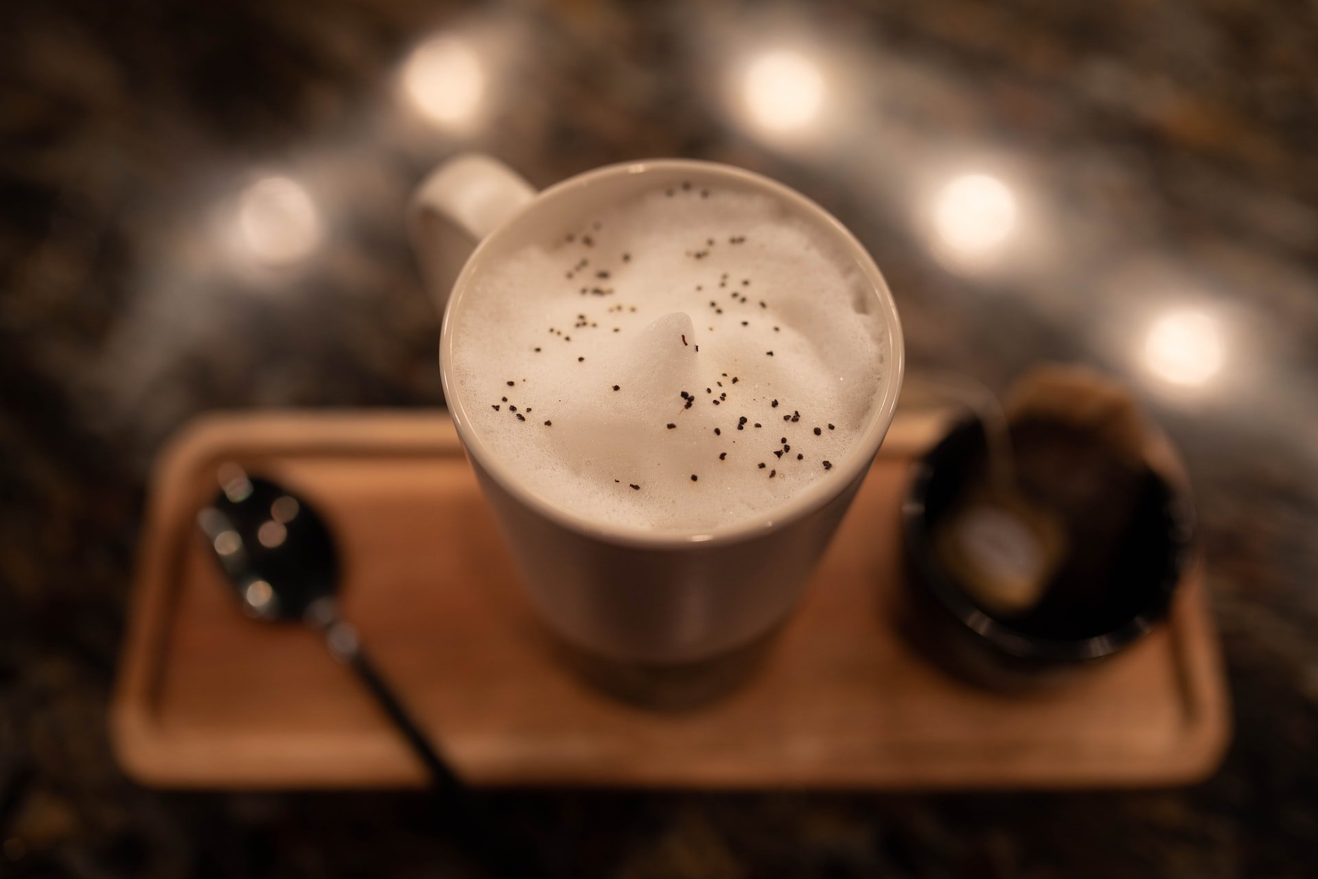 Frothy non-dairy milk on top of an Early Grey tea sweetened with vanilla in a mig on top of a bamboo try.