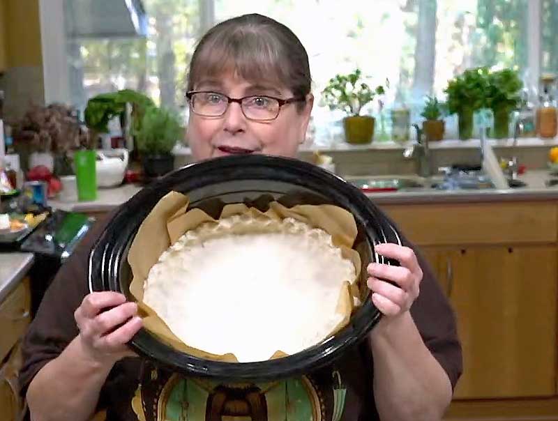 Me holding a slow cooker crock with a fluted pie crust pressed in it.
