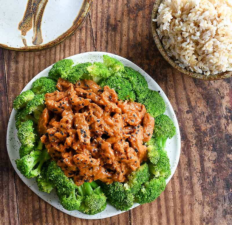 Soy Curls in spicy Asian sauce with streamed broccoli on a white plate