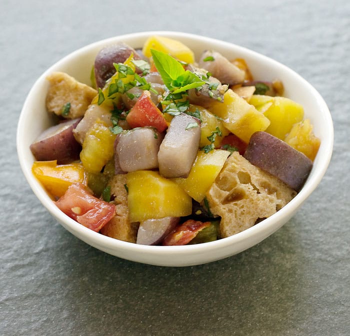 Instant Pot Potato Panzanella Salad in white bowl on a stone background.