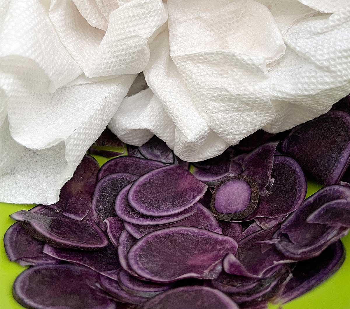 Purple potatoes being dried off with paper towels.