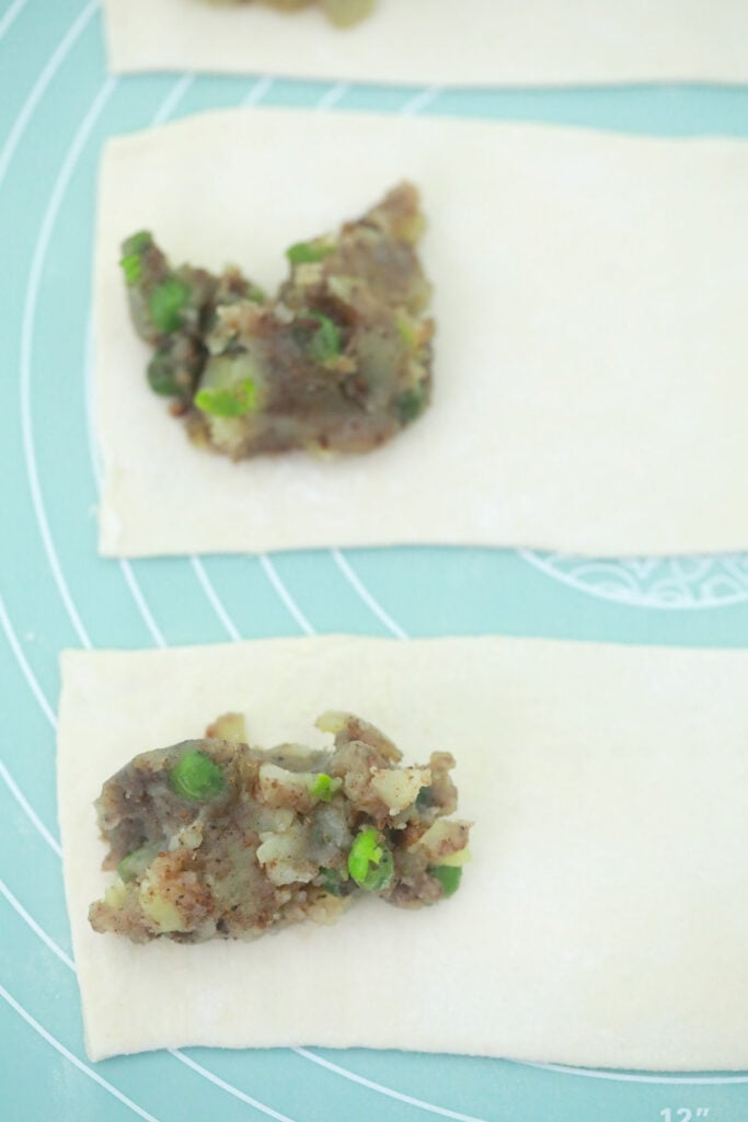 adding stuffing to vegan spring roll wrappers for easy air fryer samosas.