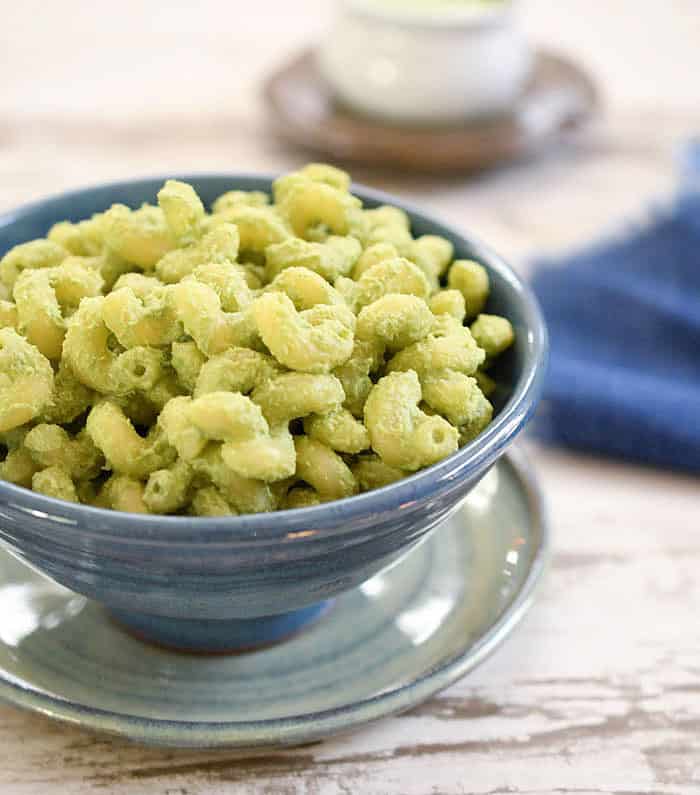Kale Stem Sauce on macaroni in a blue bowl on top of wooden table