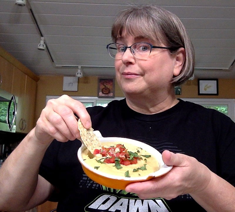 Kathy Hester dipping a tortilla chip in oat vegan queso!
