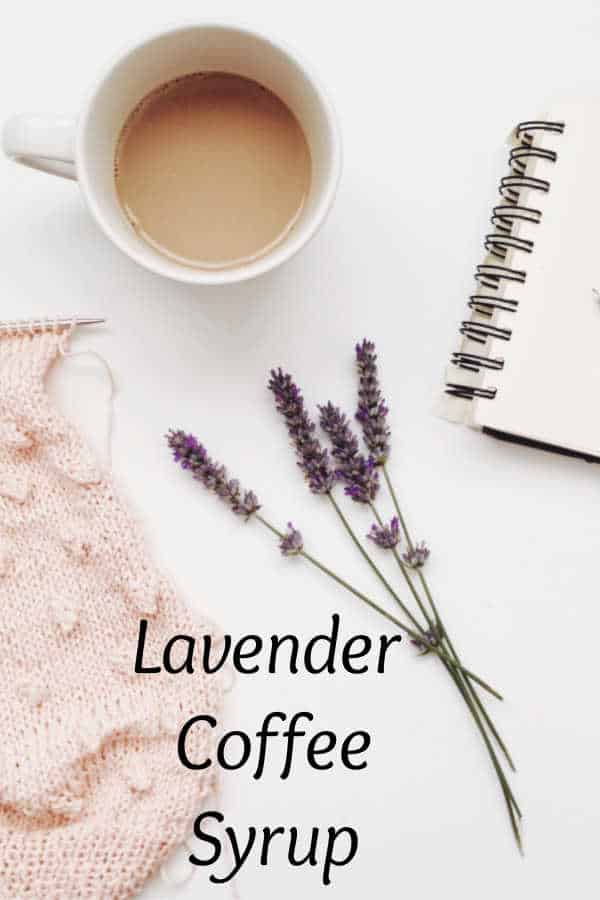 A cup of coffee with lavender syrup in a white background showing fresh lavender, knitting tools, and notepad