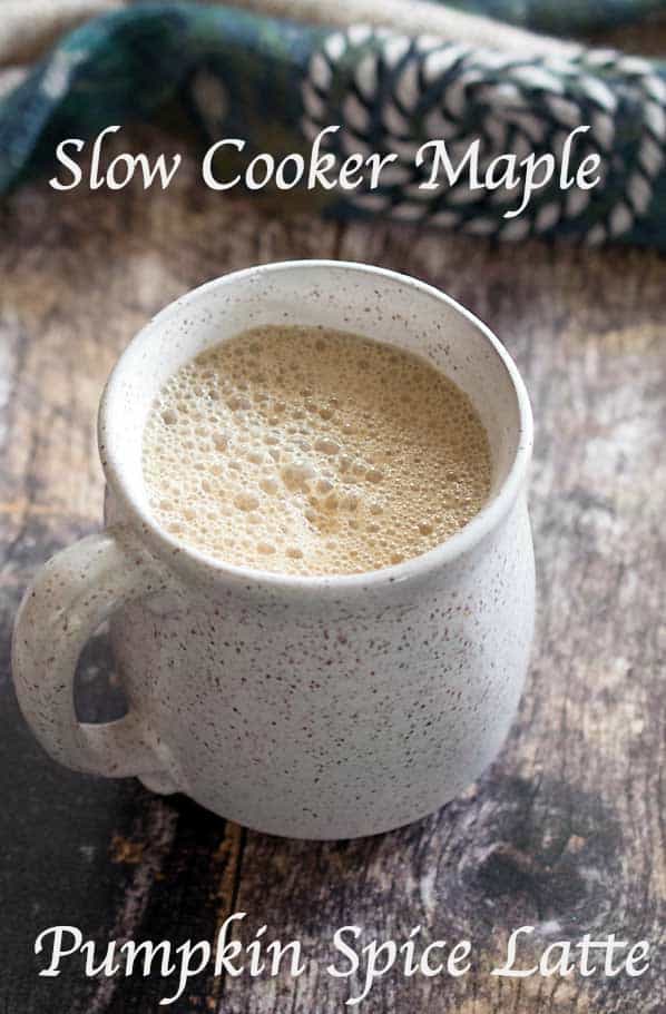 Slow Cooker vegan maple pumpkin latte in a white speckled mug with an artistic scarf on a wood surface