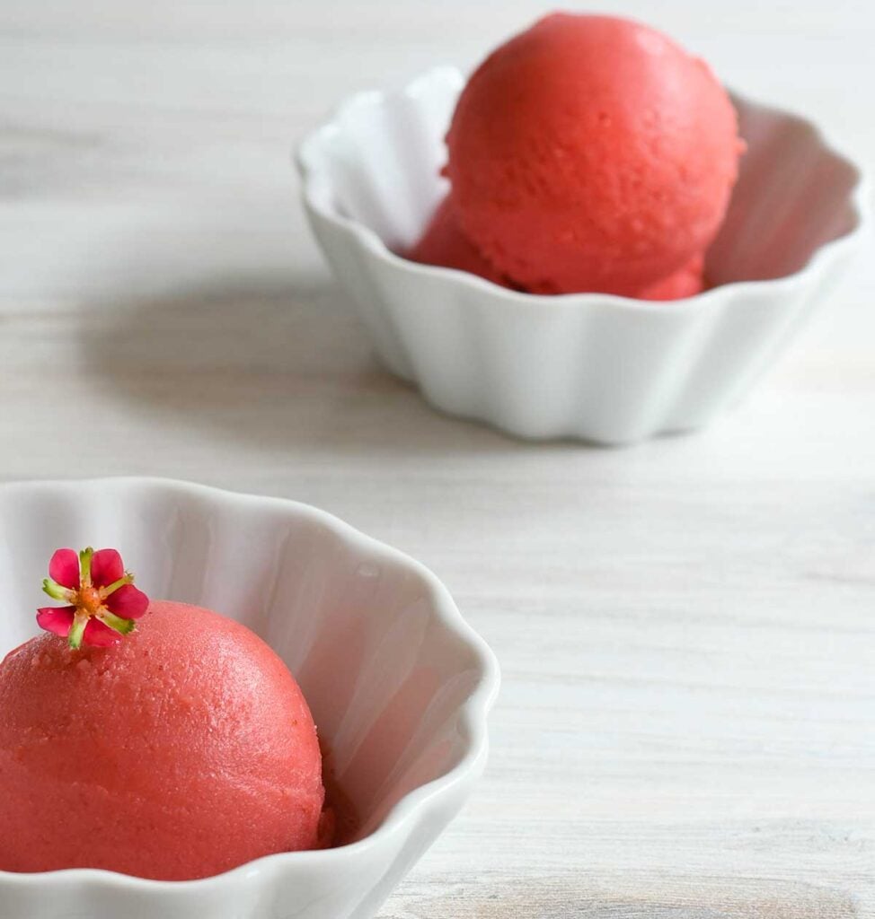 Strawberry sorbet in a white ceramic dish garnished with a strawberry flower 