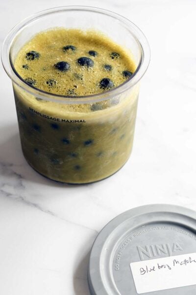 Matcha blueberry vegan ice cream frozen in a Ninja Creami pint before spinning.