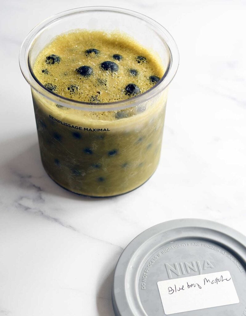 Matcha blueberry vegan ice cream frozen in a Ninja Creami pint before spinning.