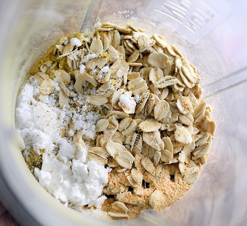 Oats, nutritional yeast, and other spices on a blender, ready to be mixed