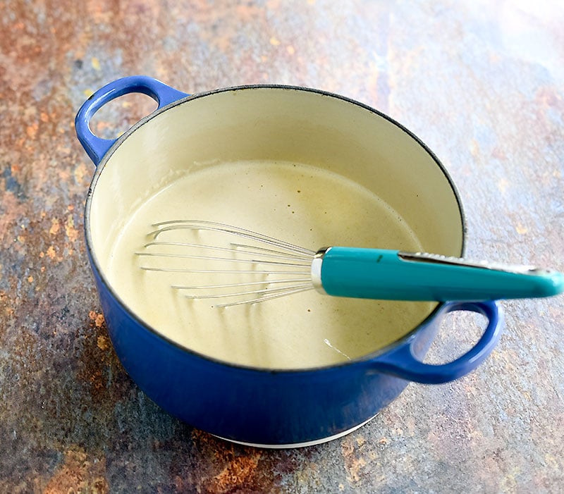 Oat mixture on a blue pan with a light blue-handled metal whisk on it