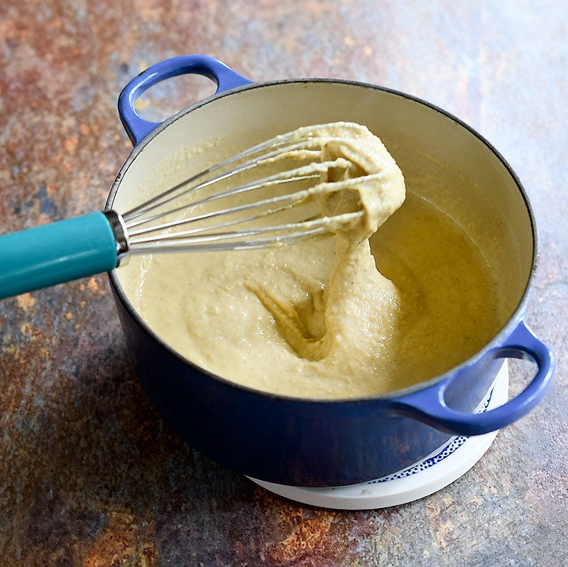 Thickened oat mixture on a blue pan being whisked