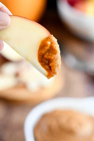 An apple slice dipped into the pumpkin dessert hummus
