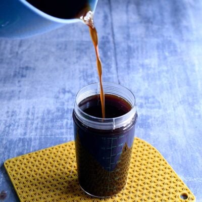 Strained vegan pumpkin spice syrup pouring into an OXO salad dressing container