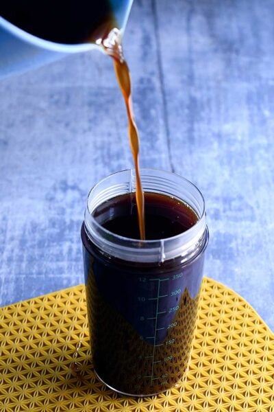 Strained vegan pumpkin spice syrup pouring into an OXO salad dressing container