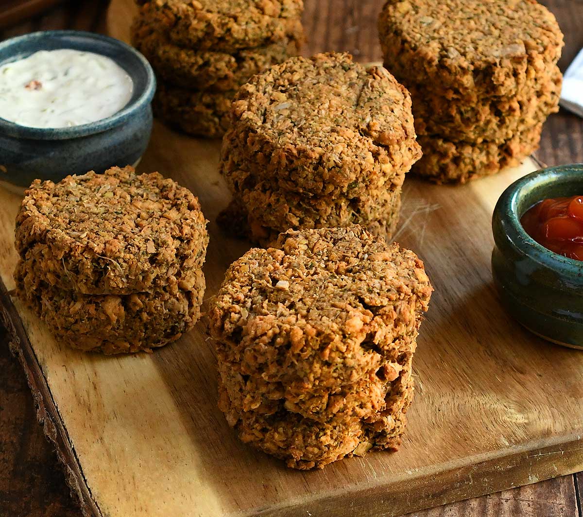 Vegan soy curl crab cakes on a wooden cutting board with dips.