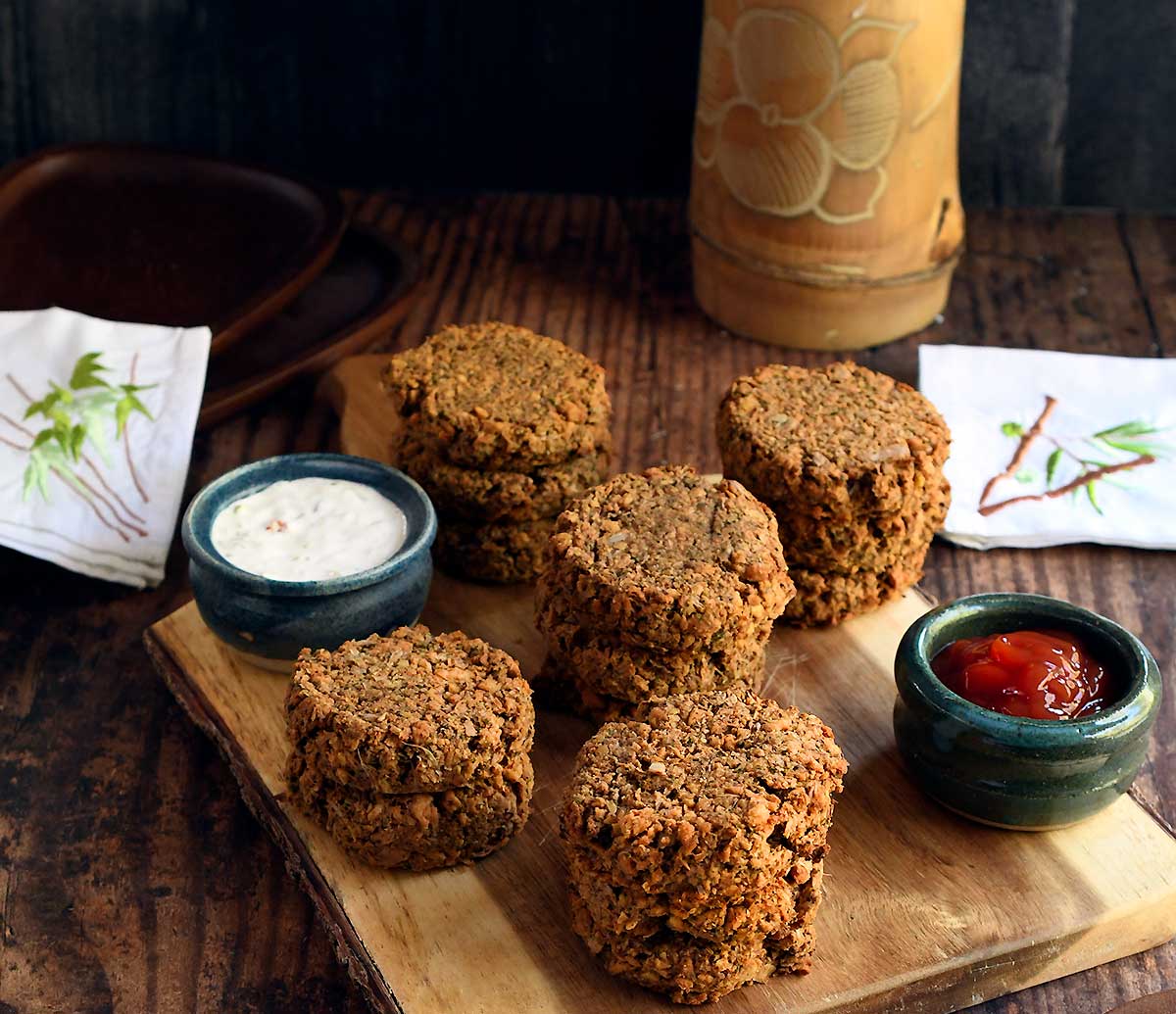 Vegetarian crab cakes made of soy curls, chickpeas, and jackfruit piled on a cutting board.
