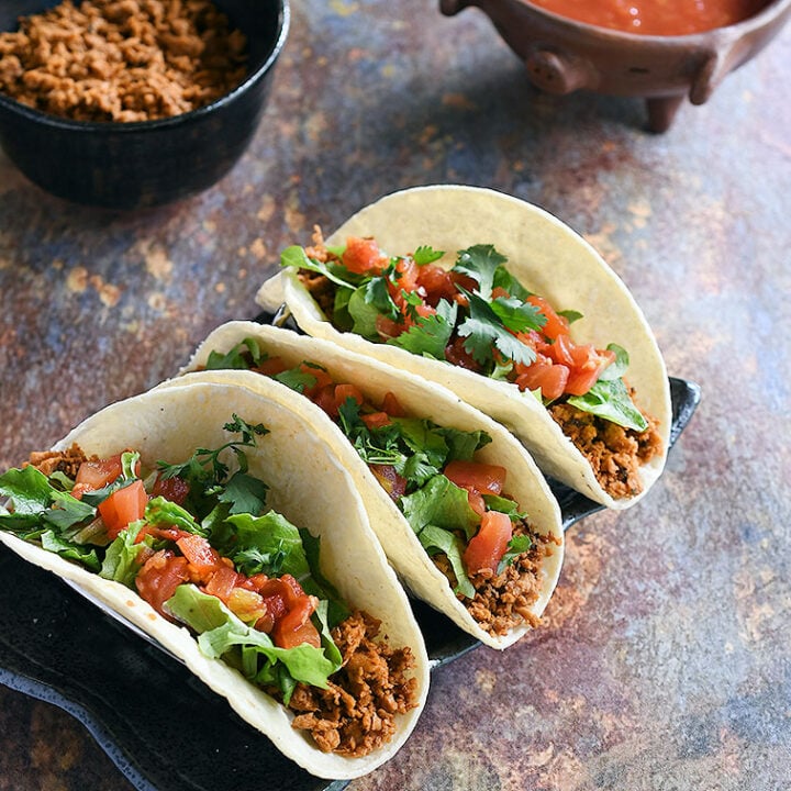 Soft tacos with minced soy curl filling topped with lettuce, chopped tomatoes, and cilantro.