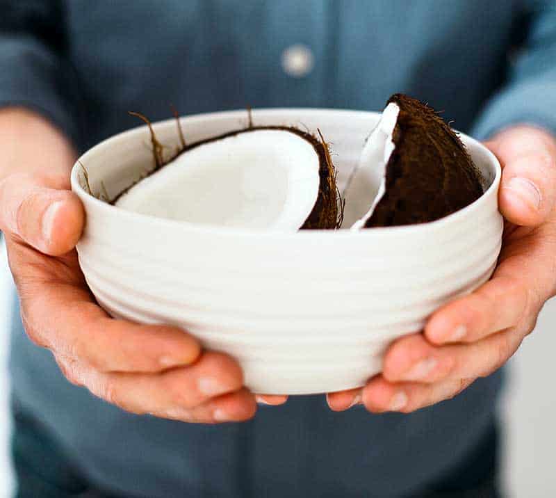 A white bowl with a coconut broken in half