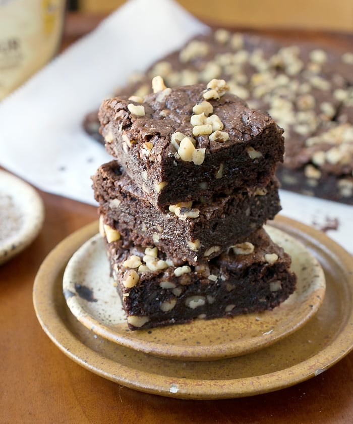 Gluten Free Vegan Teff Brownies stacked on pottery plate in from of the rest of the brownies