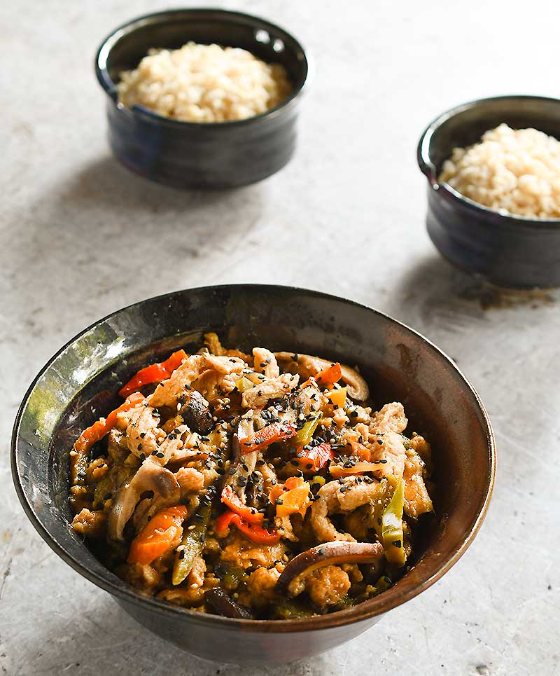 Date Sweetened Teriyaki Soy Curls in a brown ceramic bowl with 2 rice bowls
