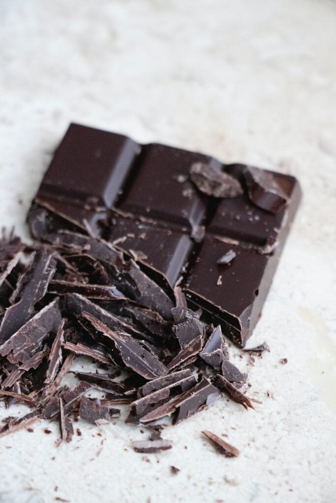 Chopped chocolate bar on white concrete counter top. It's the best feeling when you chop chocolate!