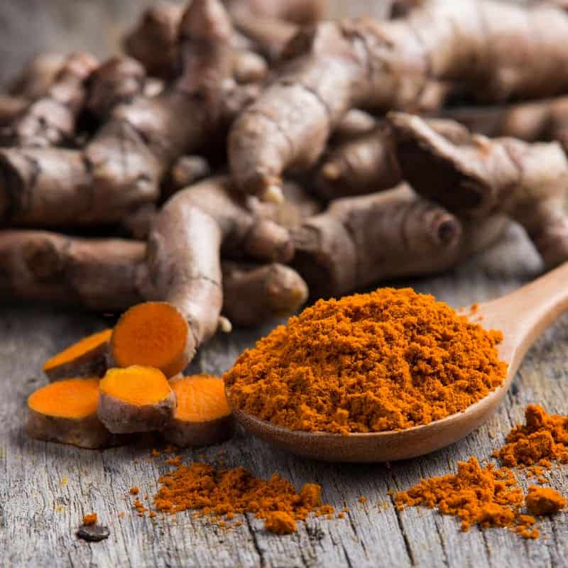 A pile of fresh turmeric roots on a wooden table