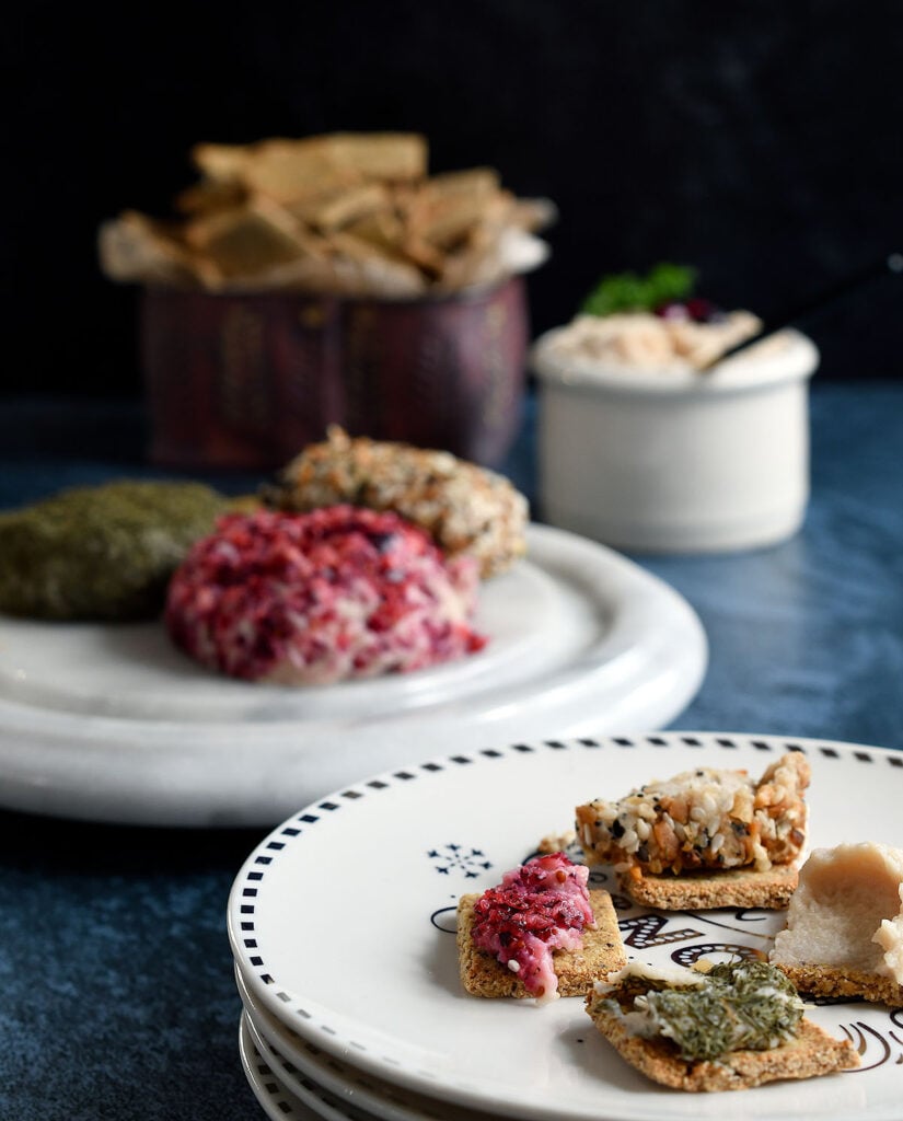 Vegan goat cheese spread and logs on a white marble cheese palte