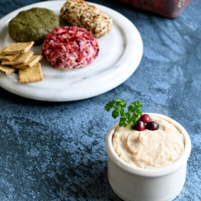 Vegan goat cheese spread and logs on a white marble cheese palte
