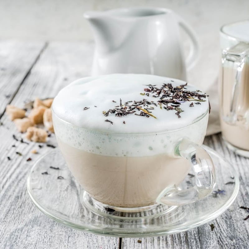 Earl Grey with frothy milk on a small cup on a wooden table top