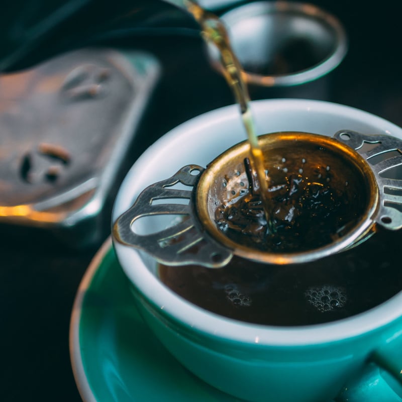 Earl Grey Tea being strained to a white cup, close up look